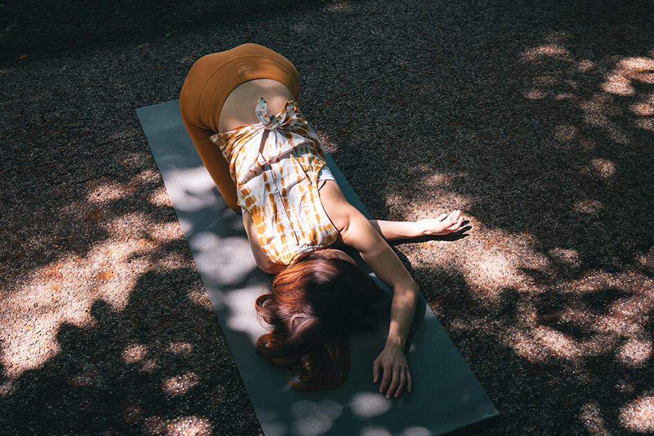 Yogamatte mit Yogi auf dem Boden, Lichtspiel durch Blätterdach