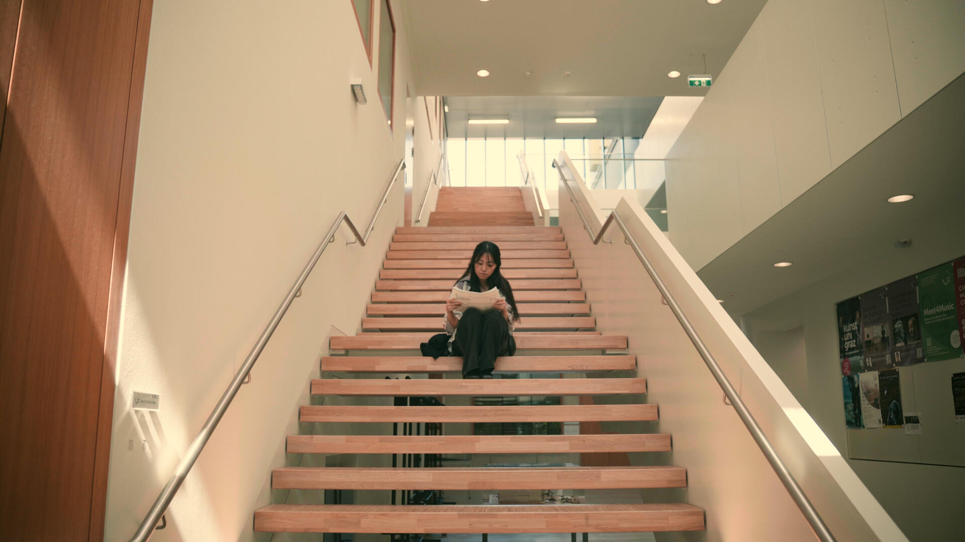Junge Frau liest auf Treppe - symmetrischer Shot